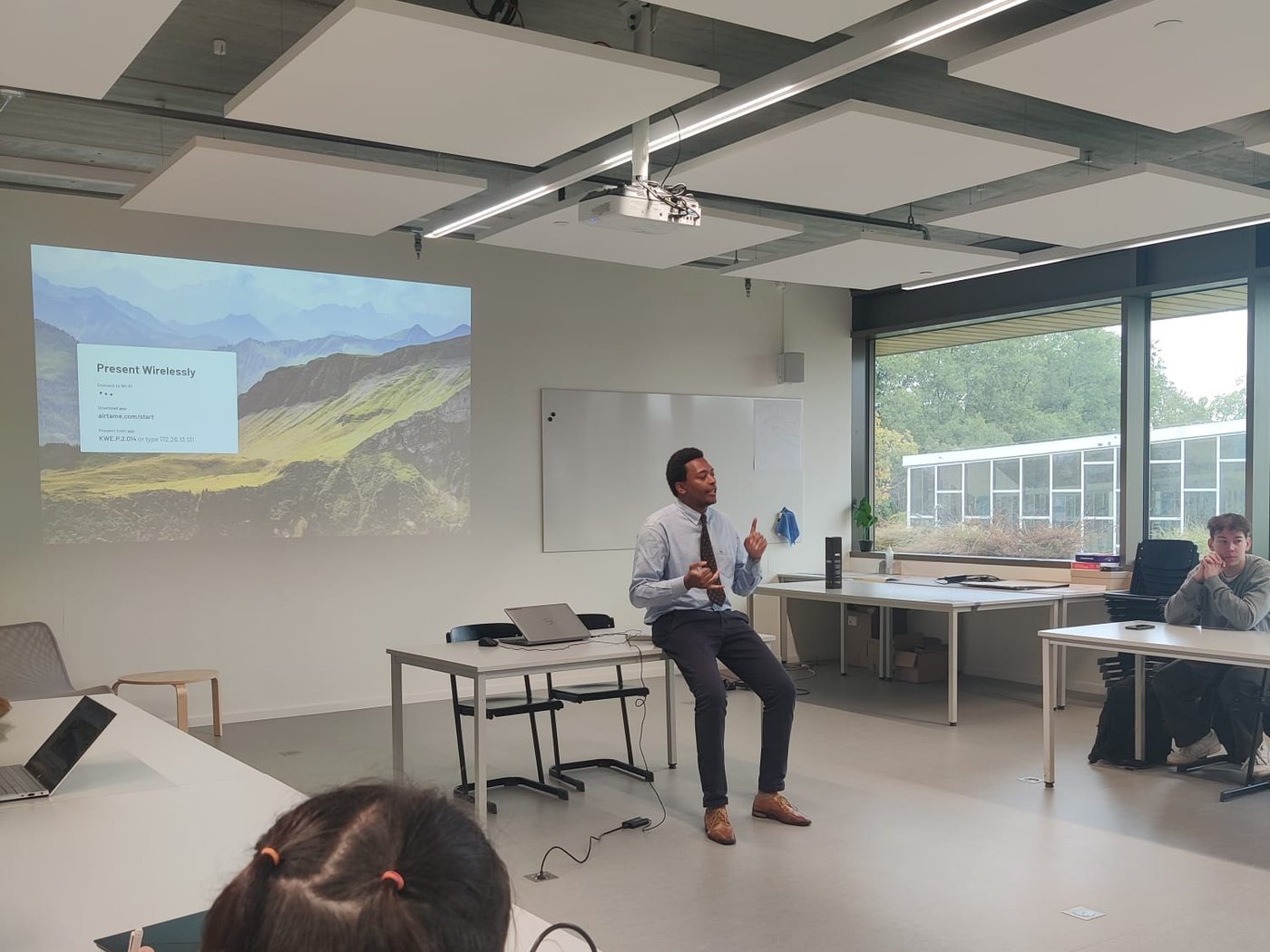 Constantin Vermoere guest-lecturing at Howest, sitting on the desk, students taking notes in the foreground